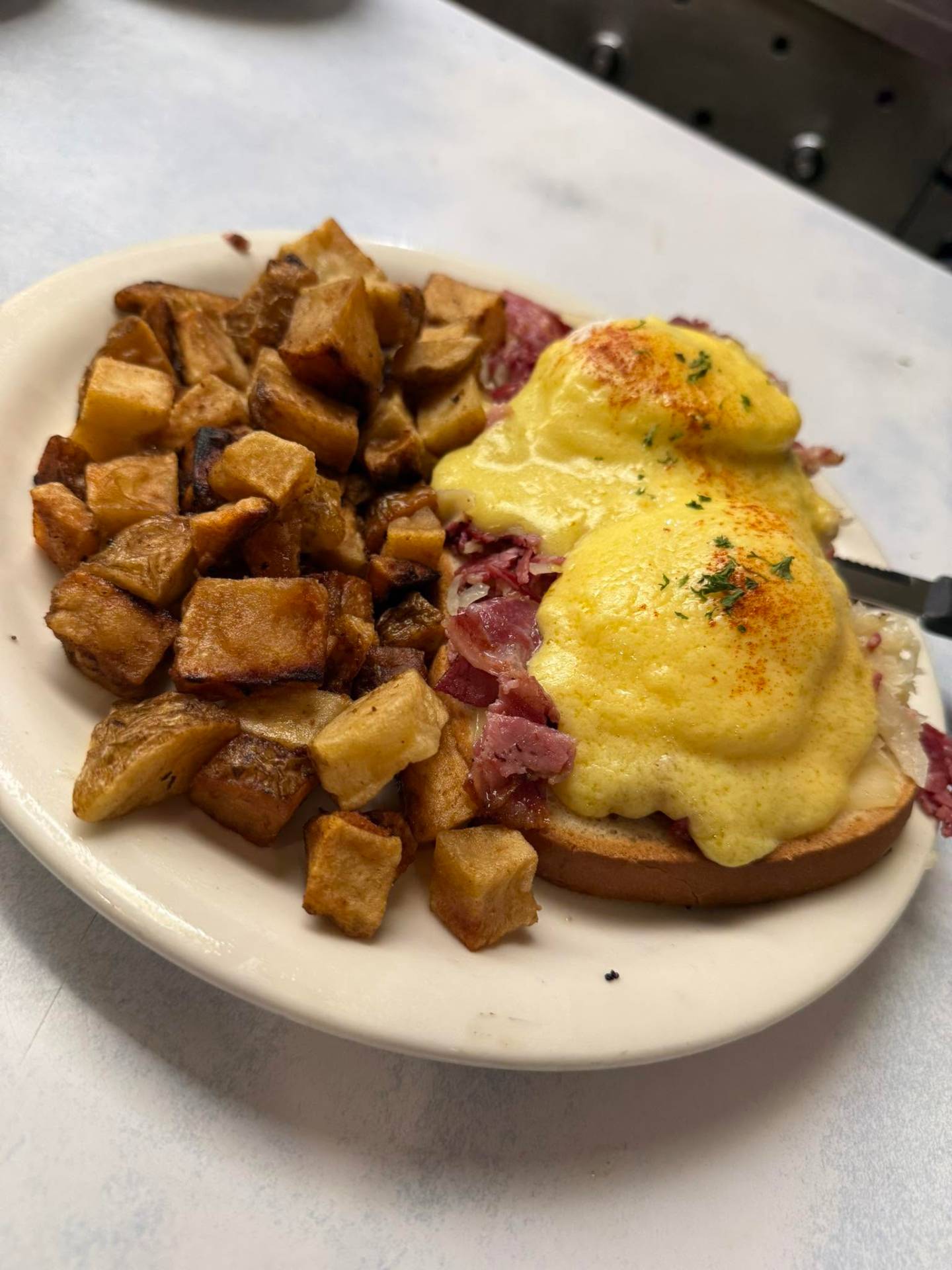 Reuben Benedict with house-made corned beef and home fries at Golden Rooster