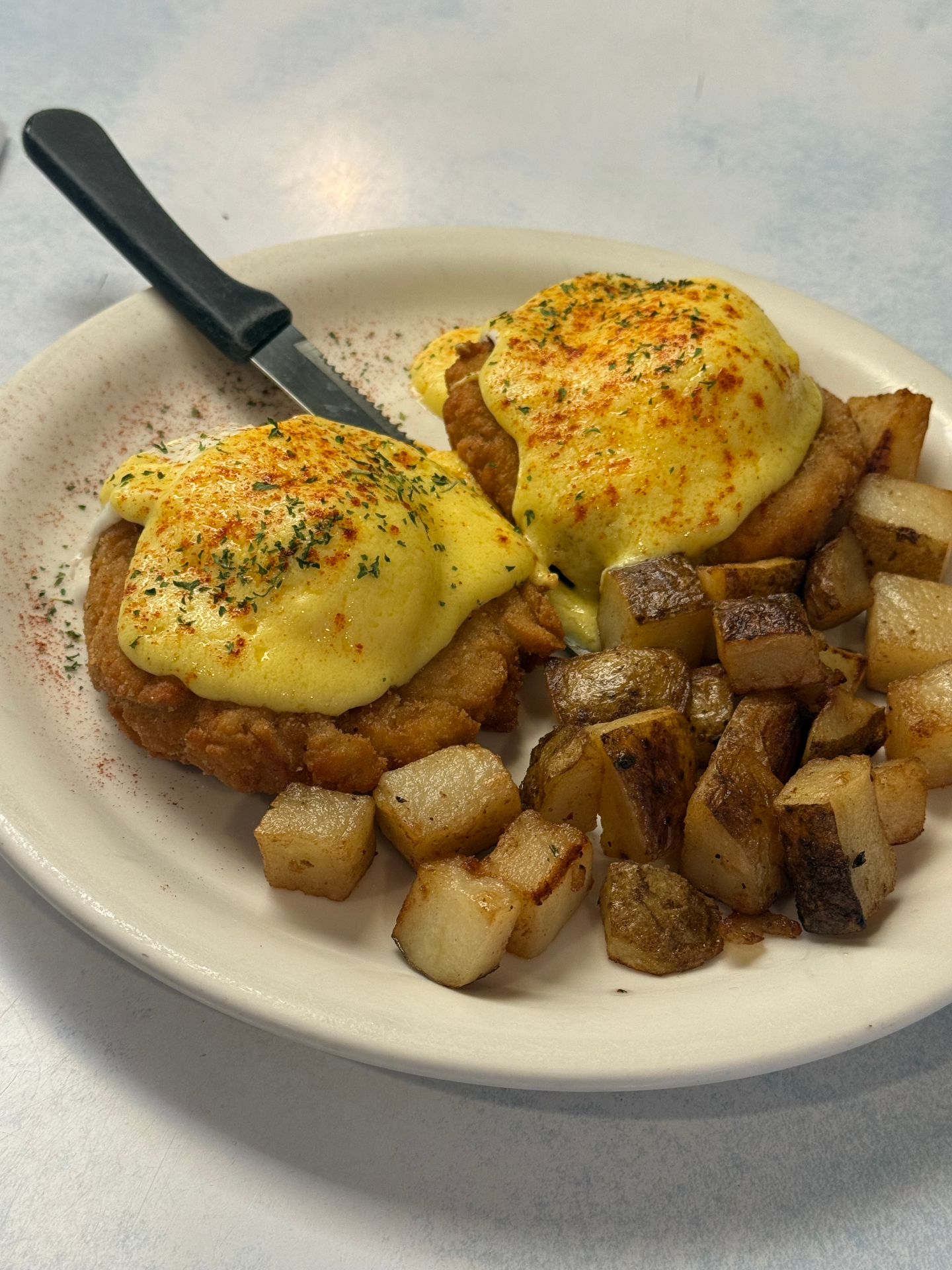 Clam cake Benedict with hollandaise and home fries