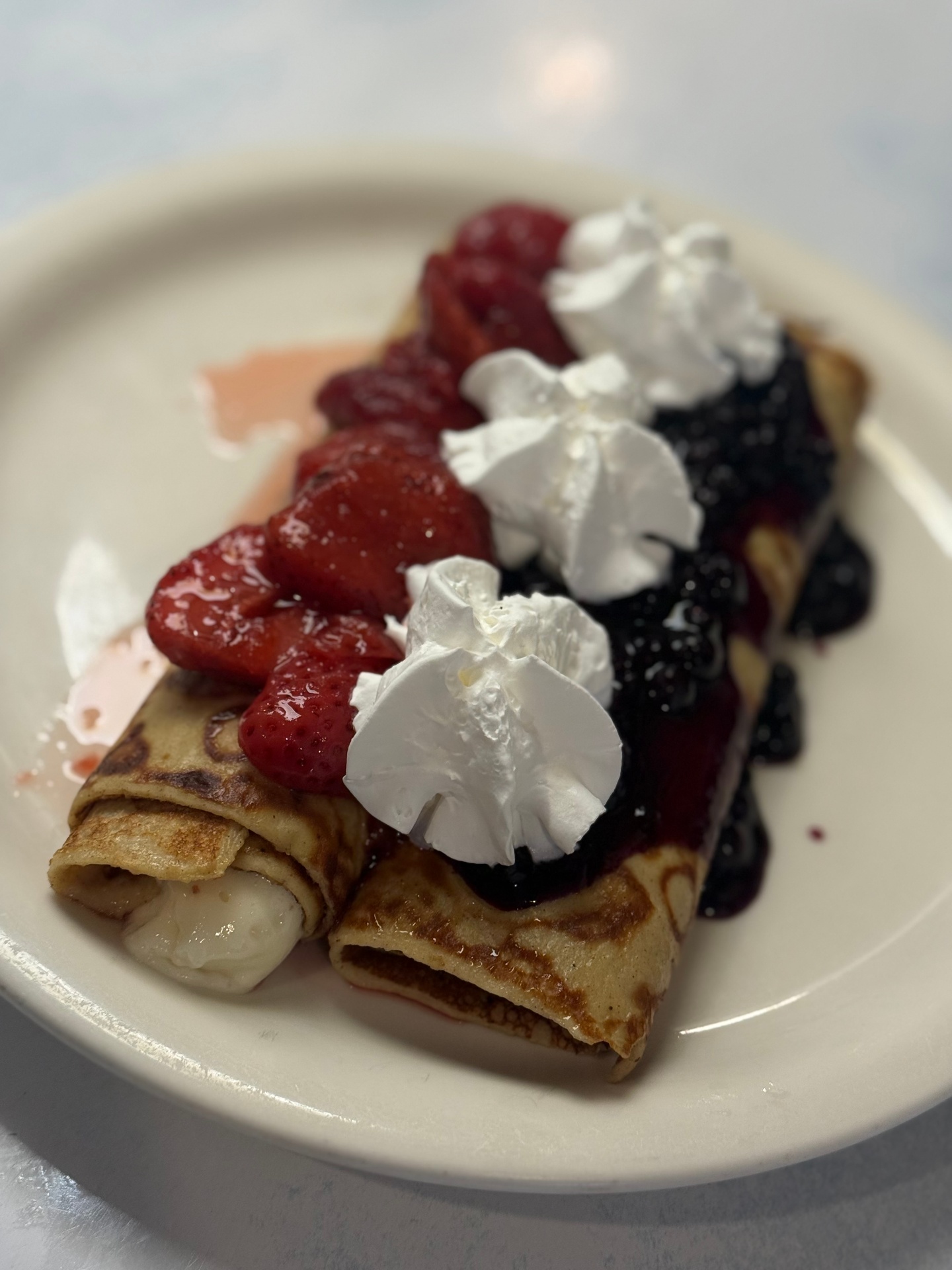 Blintzes topped with strawberries, blueberries and whipped cream